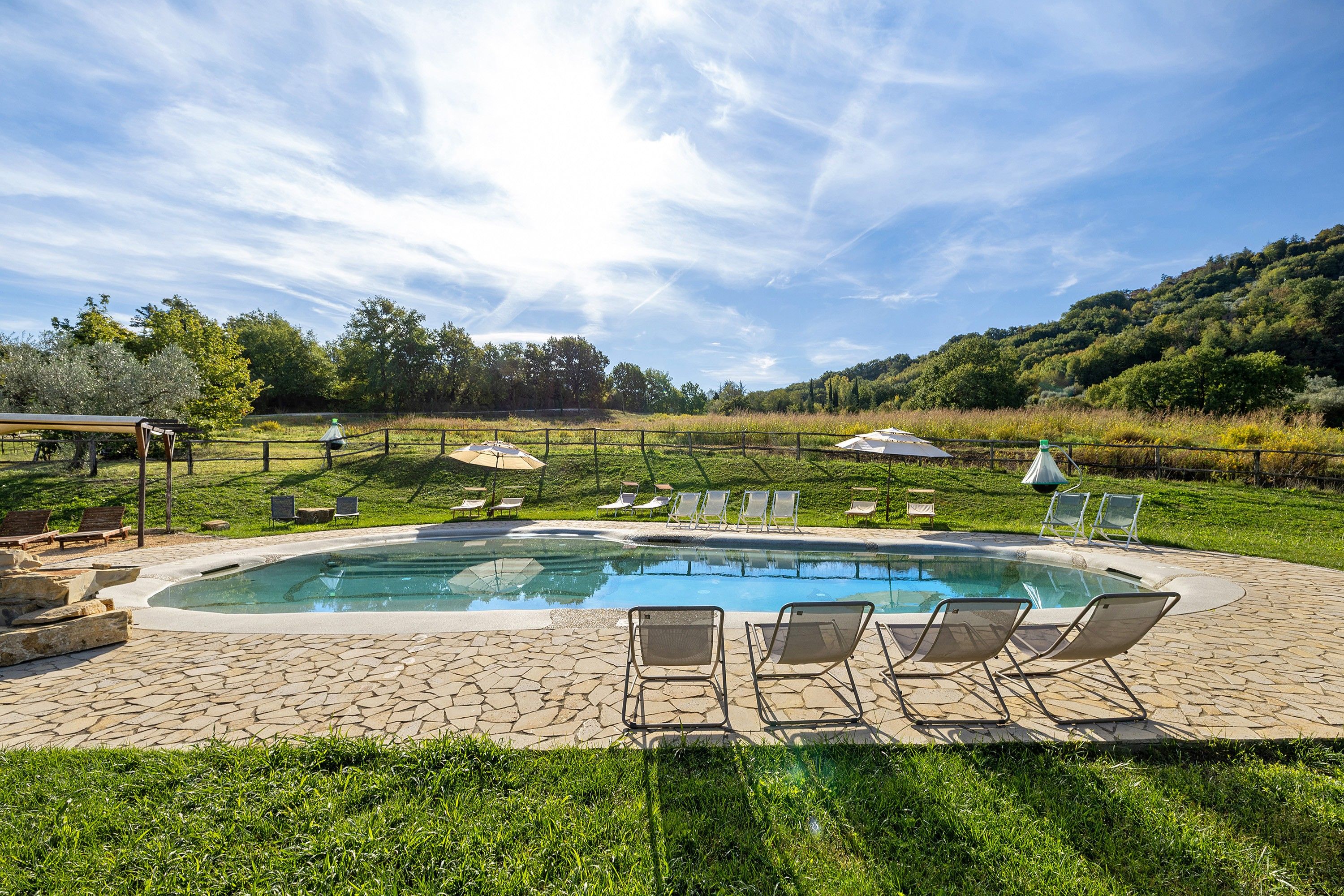 Una piscina con lettini e un patio in pietra.