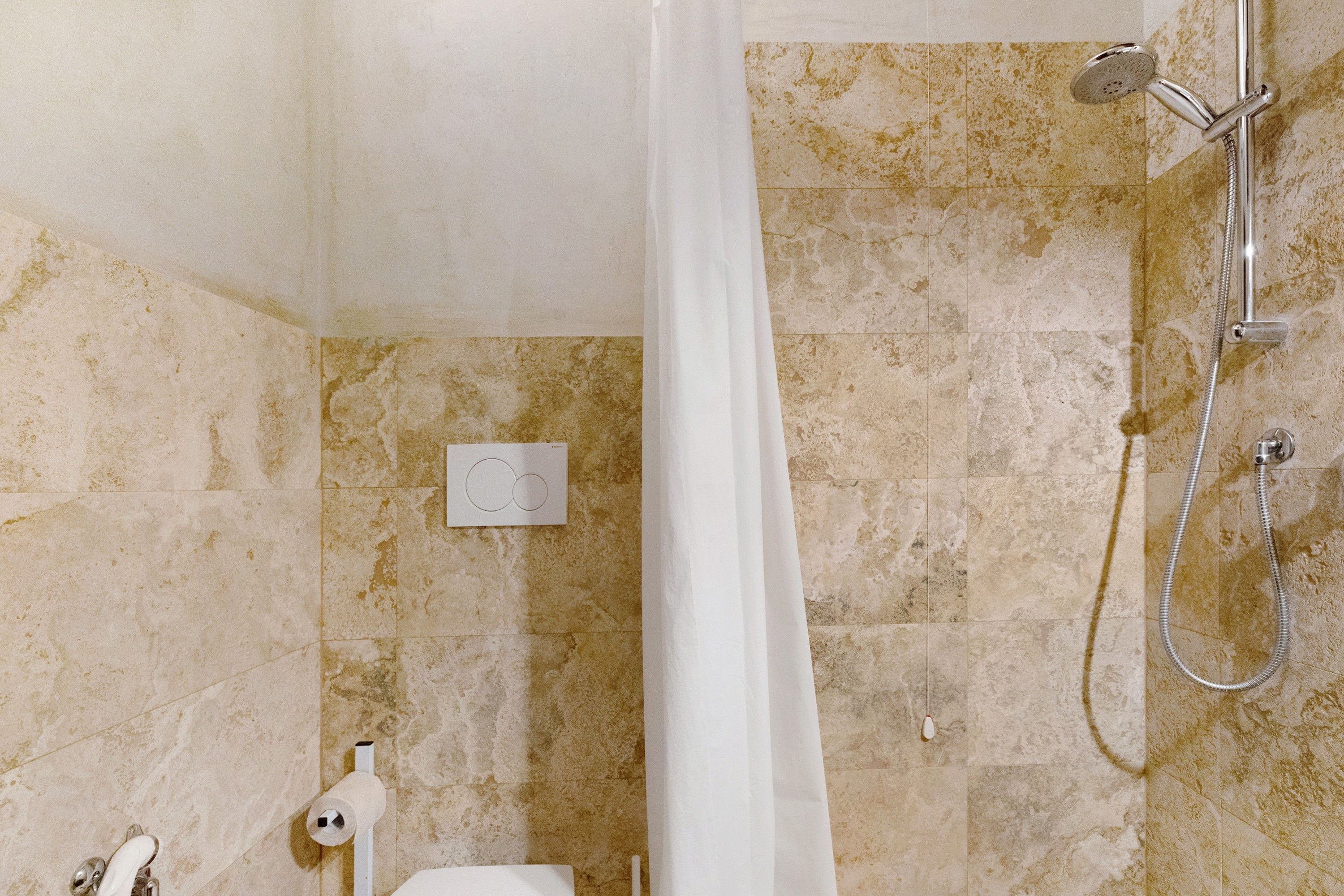 Un bagno con doccia, toilette e porta asciugamani.