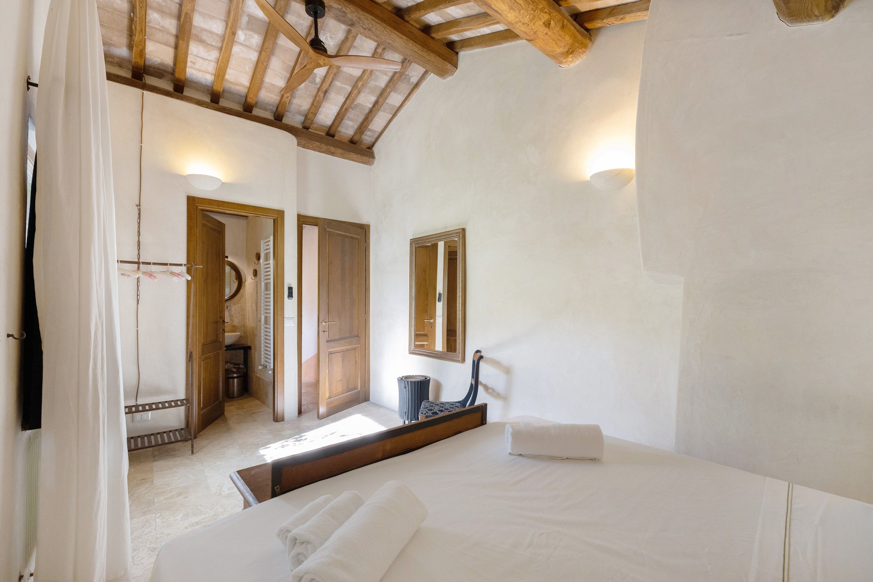 Una camera da letto con un letto, uno specchio e un soffitto in legno.