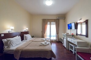 Habitación de hotel con dos camas, un escritorio, un televisor y una ventana con cortinas.