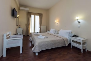 Habitación de hotel con dos camas, un escritorio, una silla, un televisor y una ventana con cortinas.