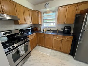 A kitchen with wooden cabinets, stainless steel appliances, a clock, and a window with blinds. - Renovated Cozy Ferndale Ranch! (Ferndale)