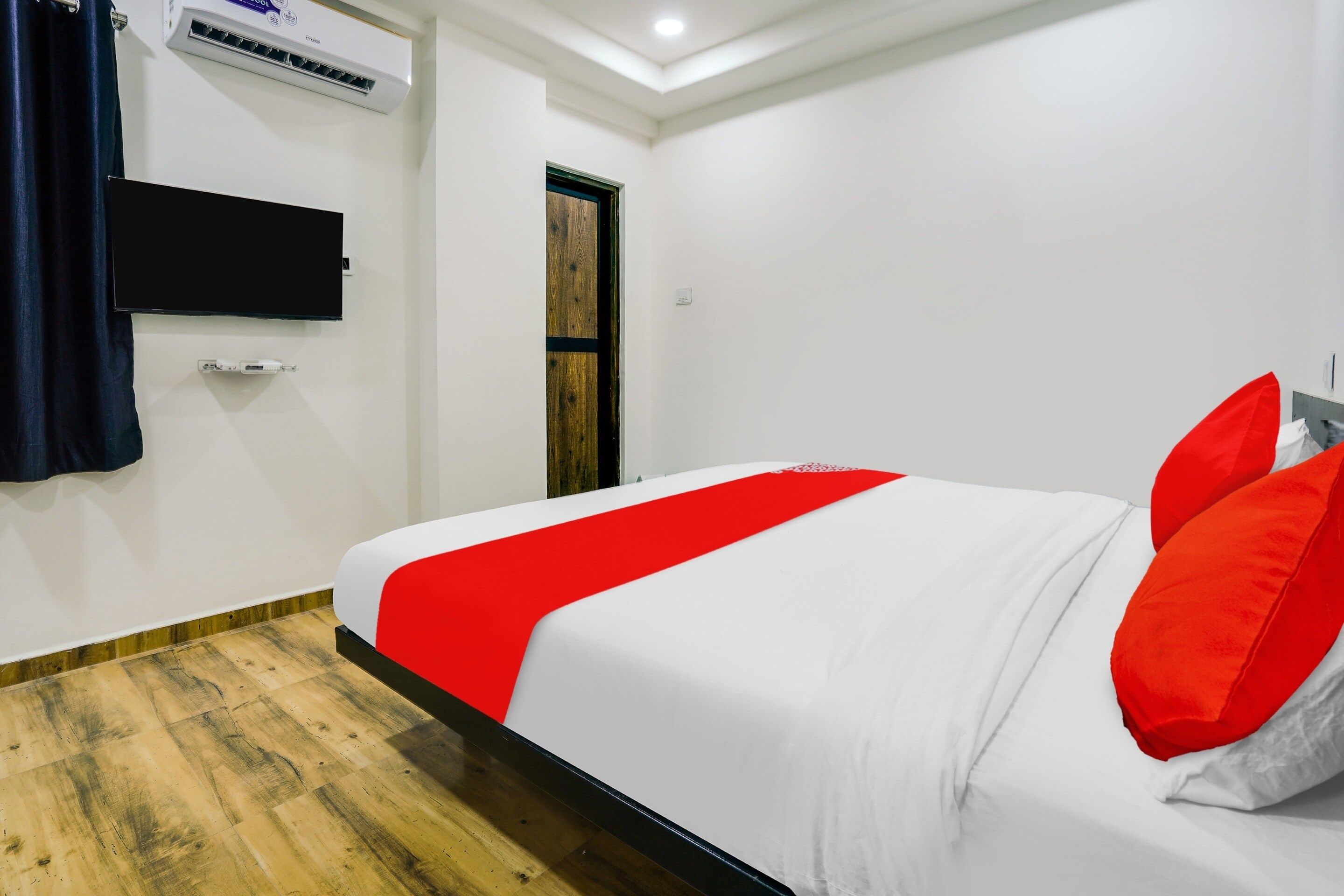 Une chambre d’hôtel équipée d’un lit, d’un téléviseur à écran plat fixé au mur, d’un système de climatisation et d’une porte en bois.