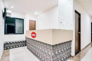 Uma área de recepção com balcão, piso de azulejos estampados, uma janela e uma porta.