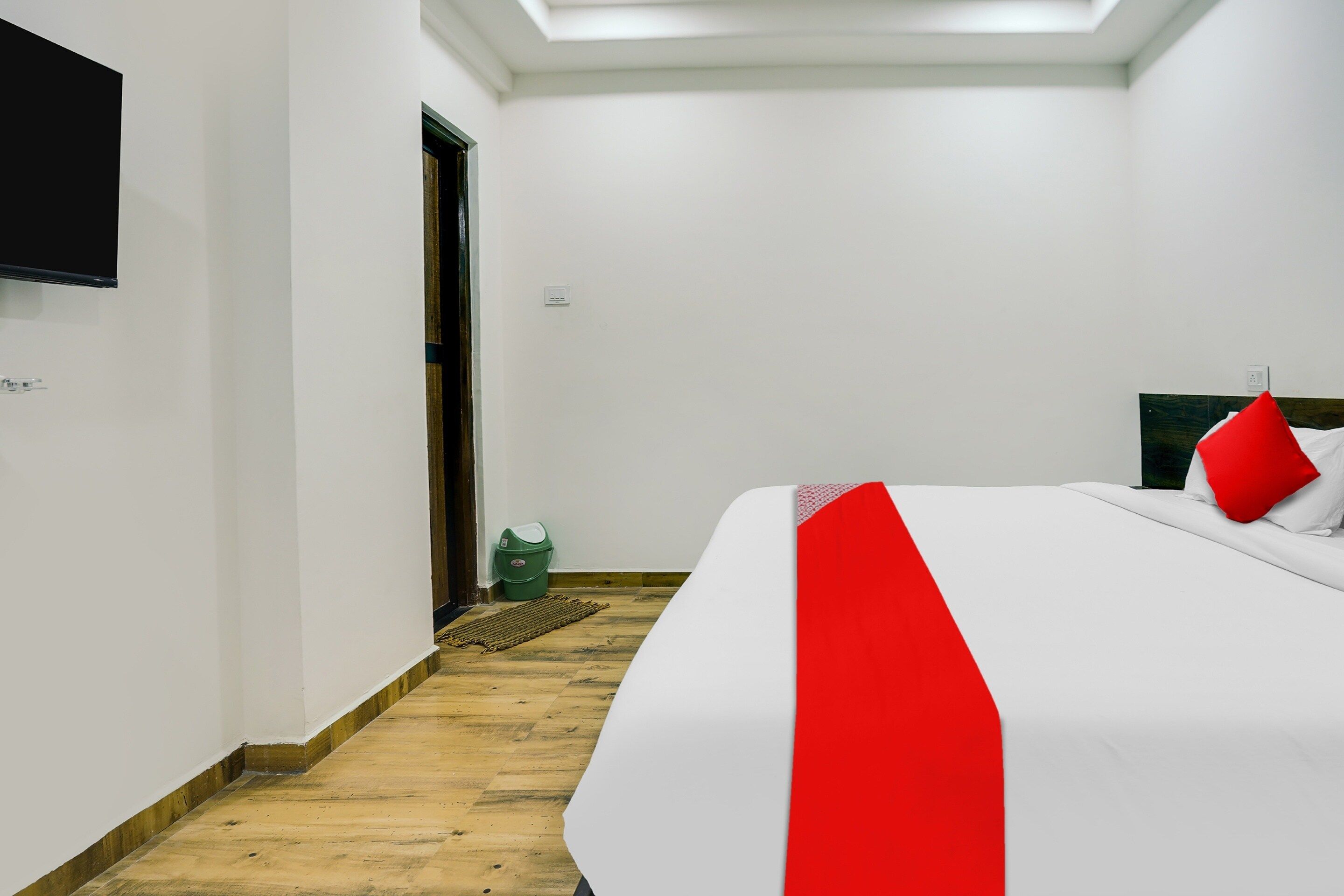 Ein Hotelzimmer mit einem Bett, einem an der Wand befestigten Fernseher und Holzboden.