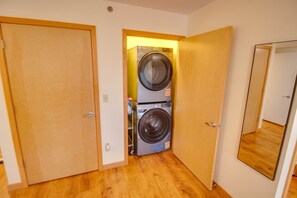 Una sala de bugaderia amb dues rentadores superposades i portes de fusta.