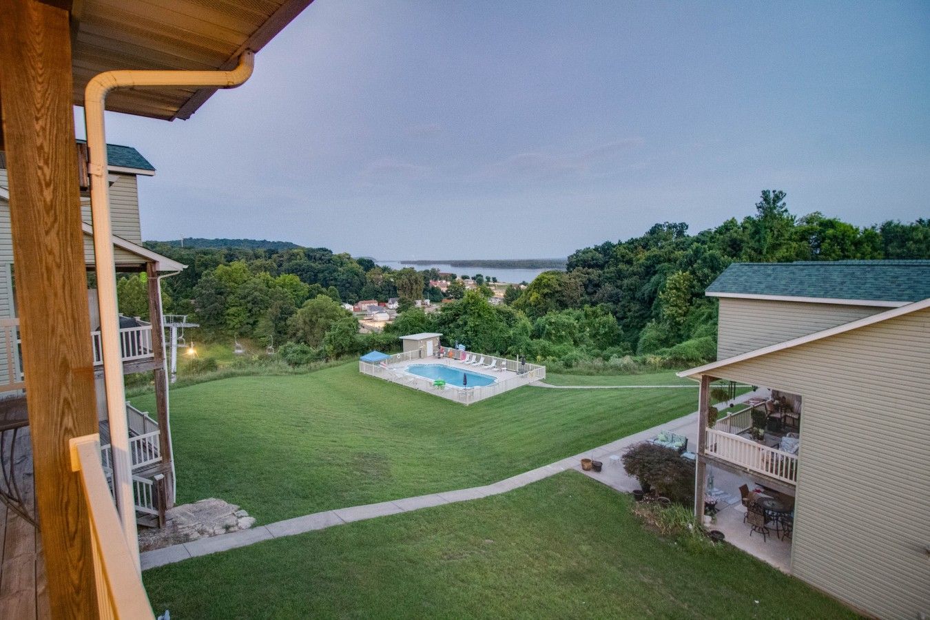 Una propiedad residencial con piscina, césped cuidado y vista a un cuerpo de agua.