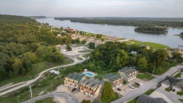 Ett bostadsområde med ett stort byggnadskomplex, en swimmingpool och en vattenyta i bakgrunden.