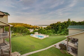 A residential property with a swimming pool, a covered patio, and a view of a lake.