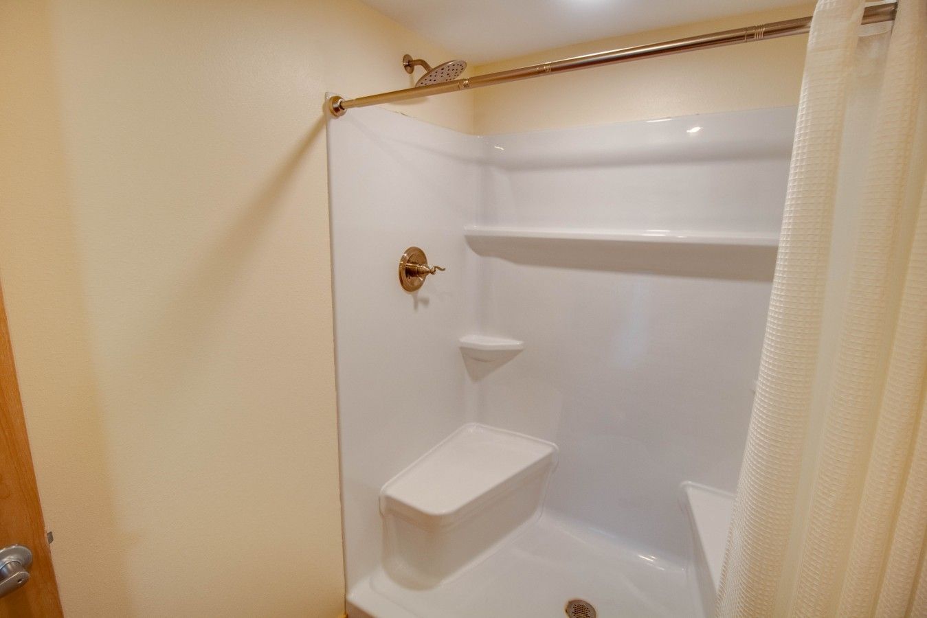 Un box de ducha con puerta de vidrio, un perchero y un estante.