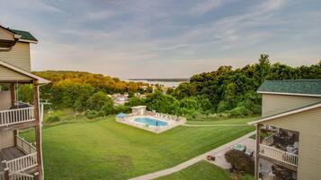 Una propiedad residencial con piscina, un patio cubierto y vista a un lago.