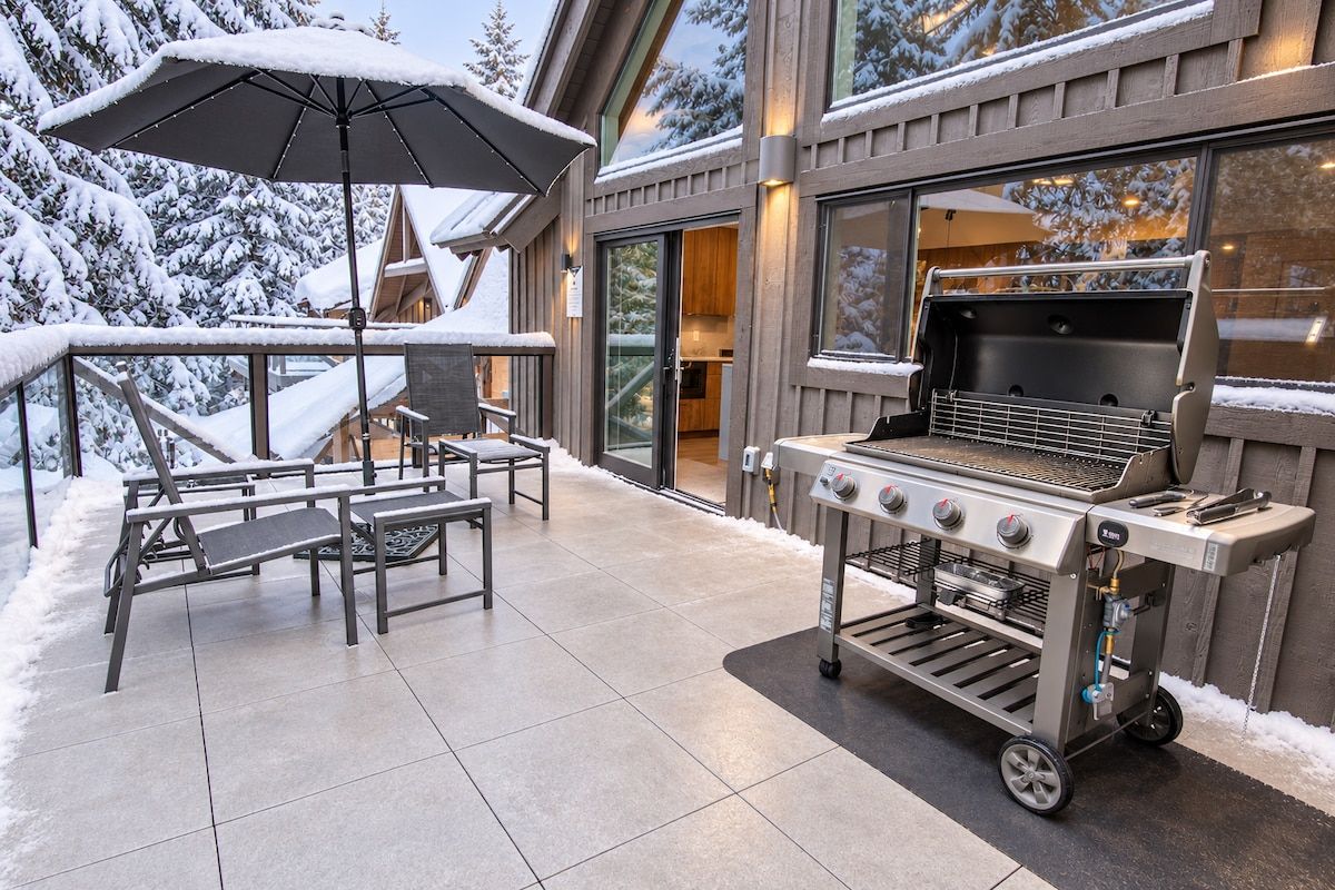 Eine Terrassengruppe im Freien mit Grill, Sitzgelegenheiten und verschneiter Landschaft.