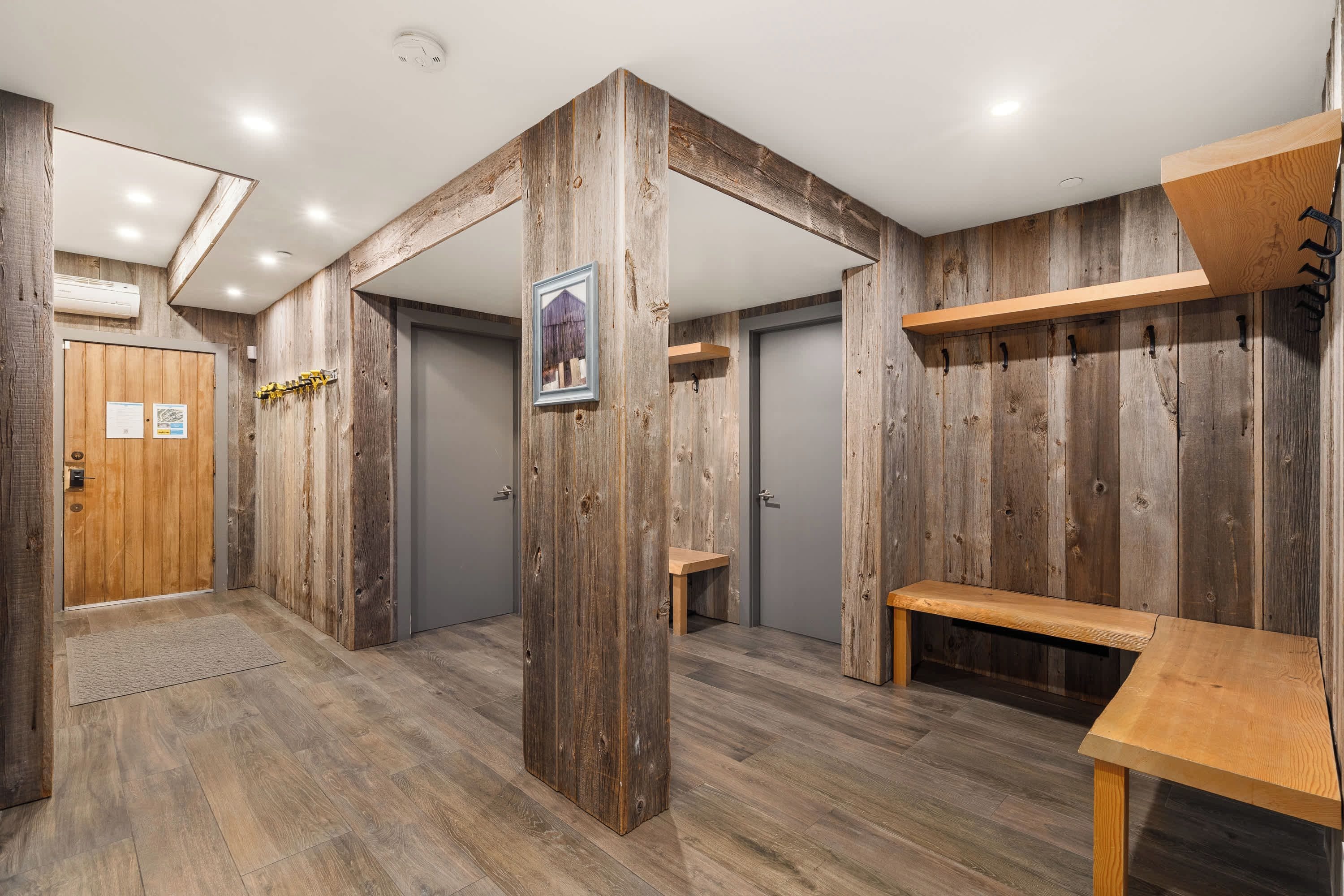 A room with wooden walls, a wooden bench, a door, and a small table.