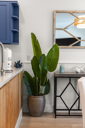 Cozinha moderna com planta em vaso, cafeteira e peixe decorativo no balcão.