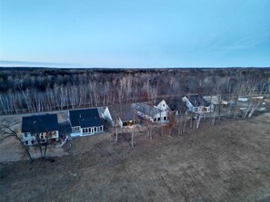 An aerial view of a residential area with multiple houses, a clear sky, and a flat terrain. - Villa 15 on Preserve Golf Course! (Pequot Lakes)