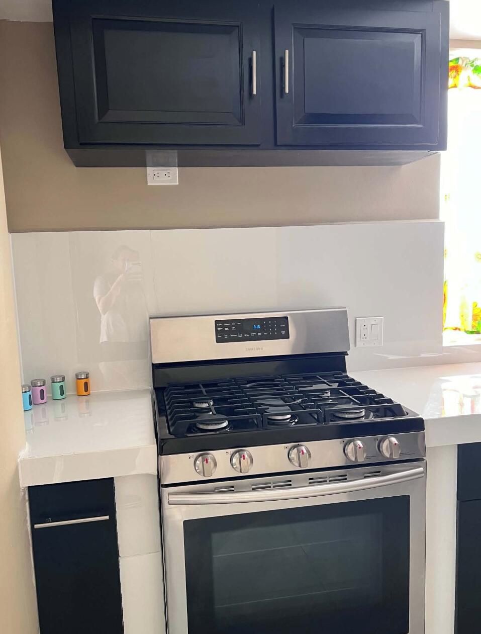 A kitchen with a stainless steel stove, oven, and black cabinets above.