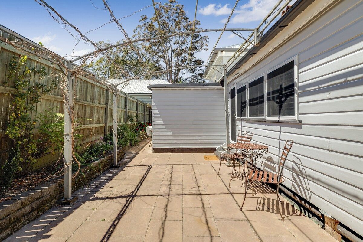 A patio area with a table and chairs, a covered seating area, and a garden with climbing plants.