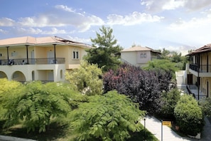 A residential area with multi-story buildings, a pathway, and lush greenery. - Portes Beach Hotel (Nea Propontida)