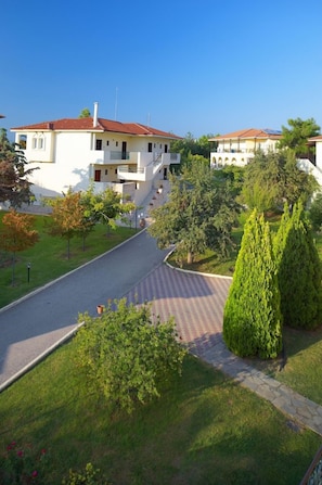 A residential area with a paved road, a stone pathway, and a row of houses with red roofs. - Portes Beach Hotel (Nea Propontida)