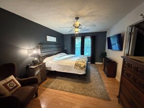 A bedroom with a bed, a nightstand, a lamp, a chair, a dresser, a television, and a ceiling fan. - 3-bedroom house in delightful Decatur with cool AC breeze (Decatur)