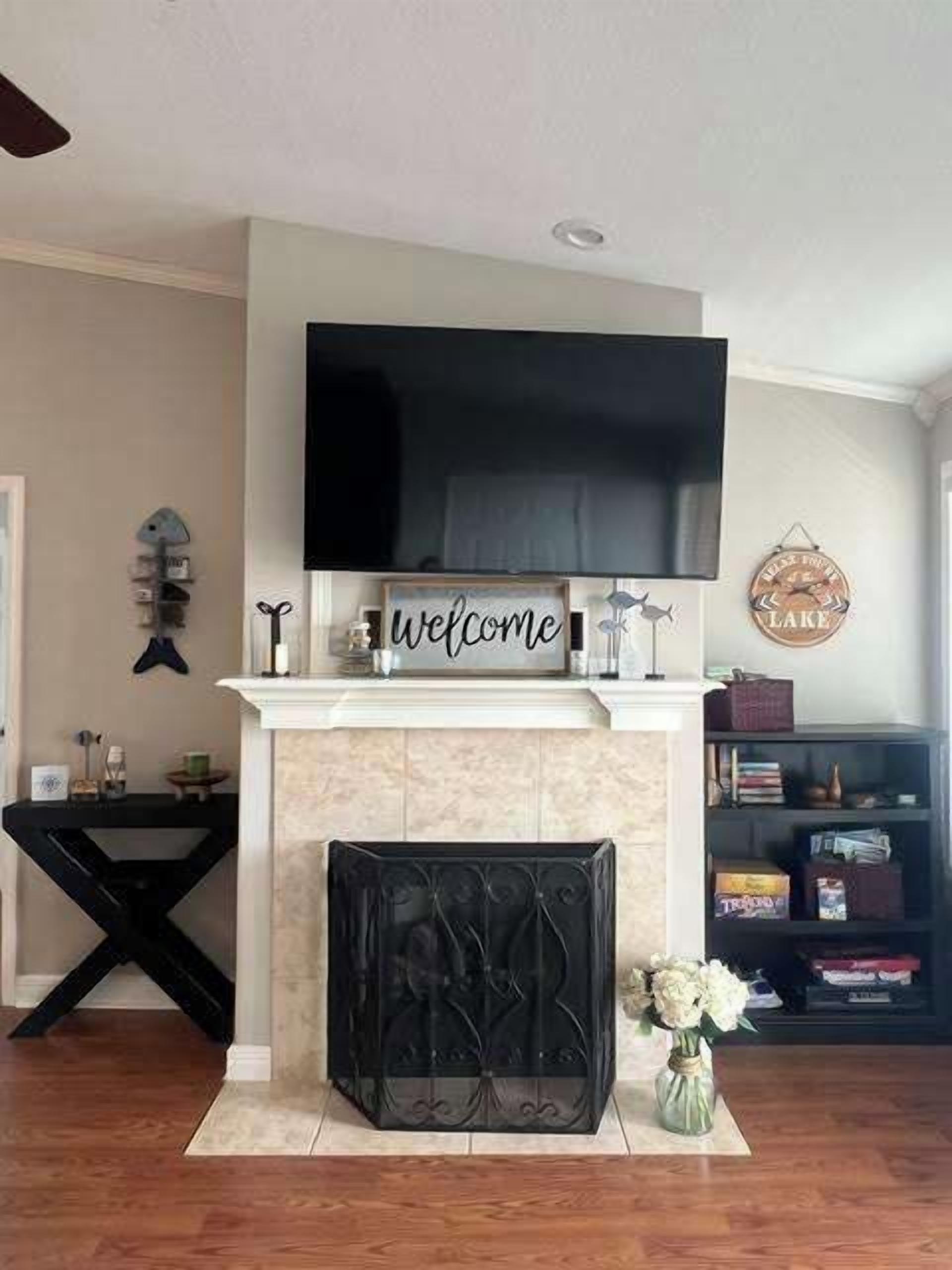Una sala de estar con chimenea, un televisor de pantalla plana montado arriba y un letrero de bienvenida.