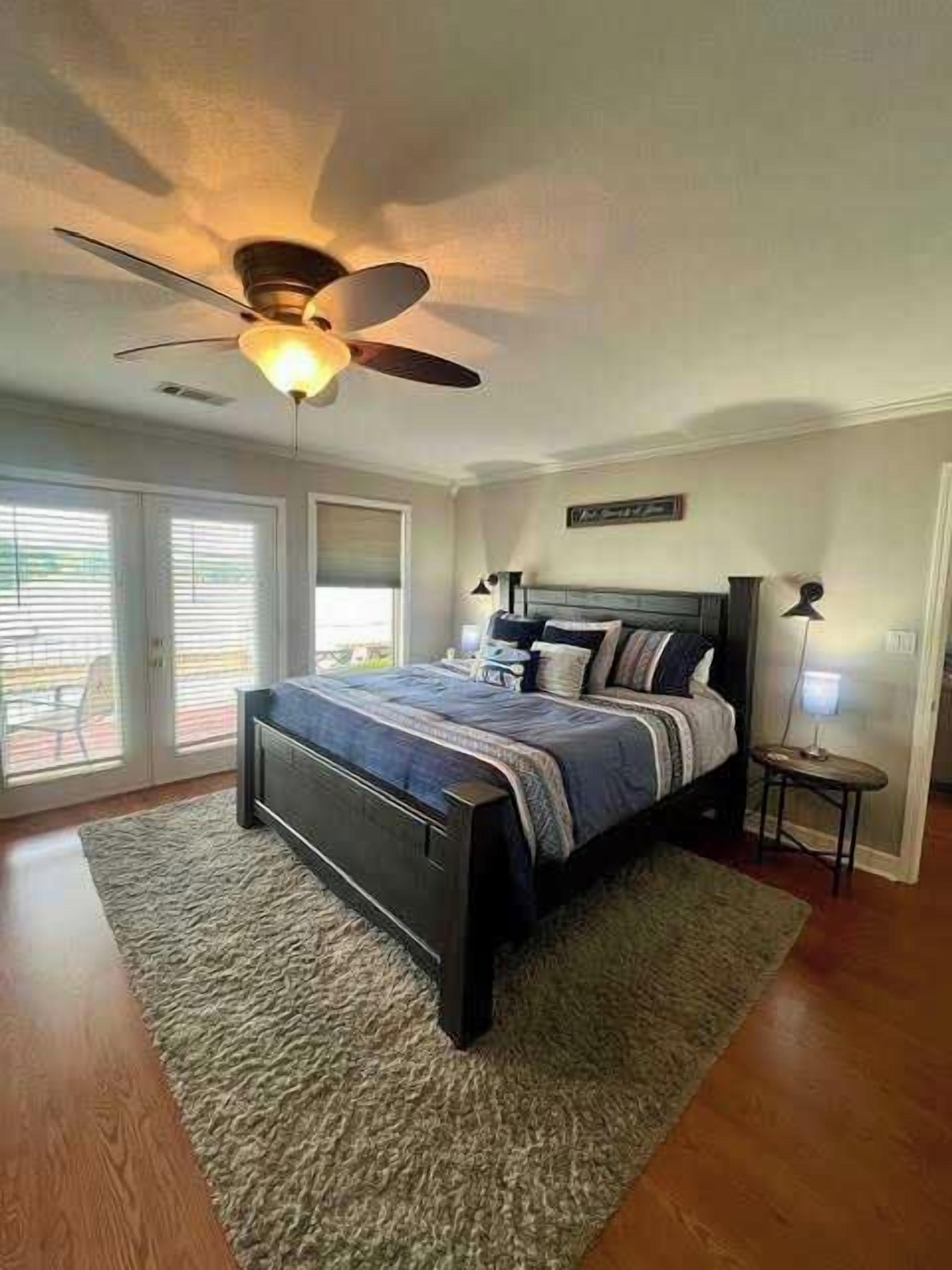 Ein Schlafzimmer mit einem Bett, einem Deckenventilator und Blick durch die Glastüren.
