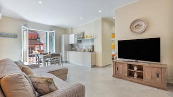 Una sala de estar moderna con un televisor de pantalla plana, un sofá y un comedor con sillas y una mesa.