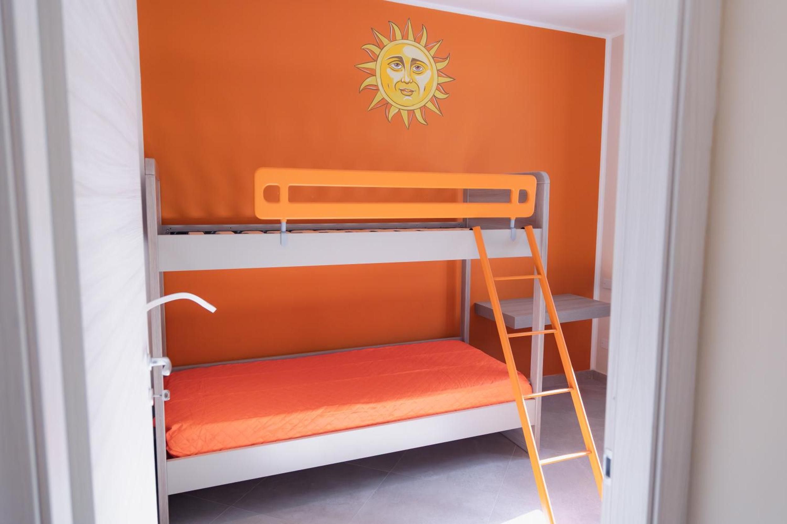 Una cama litera con una pared naranja y una decoración de sol.