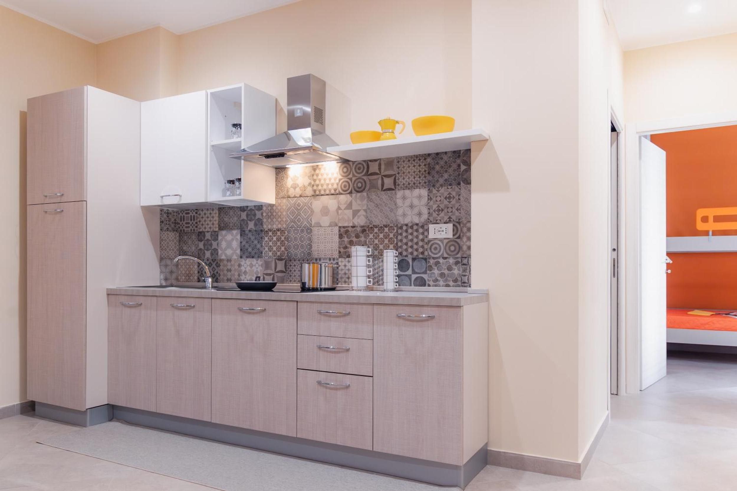 Eine moderne Küche mit eingebautem Herd, Spüle und Arbeitsplatte. Ein Schrank mit Schubladen und einem Regal befindet sich über der Arbeitsfläche.