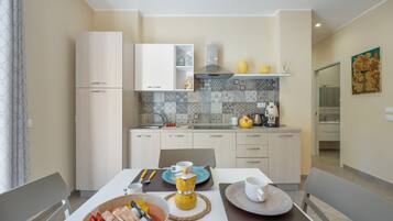 A modern kitchen with light-colored cabinets, a tiled backsplash, and a dining area with a table set for two.