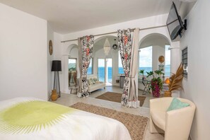 Ein geräumiges Schlafzimmer mit einem großen Bett, einer Sitzecke mit einer Couch und Meerblick.