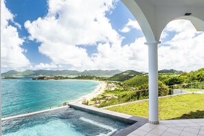 Ein Küstenblick mit Pool, Strand und Bergen im Hintergrund.