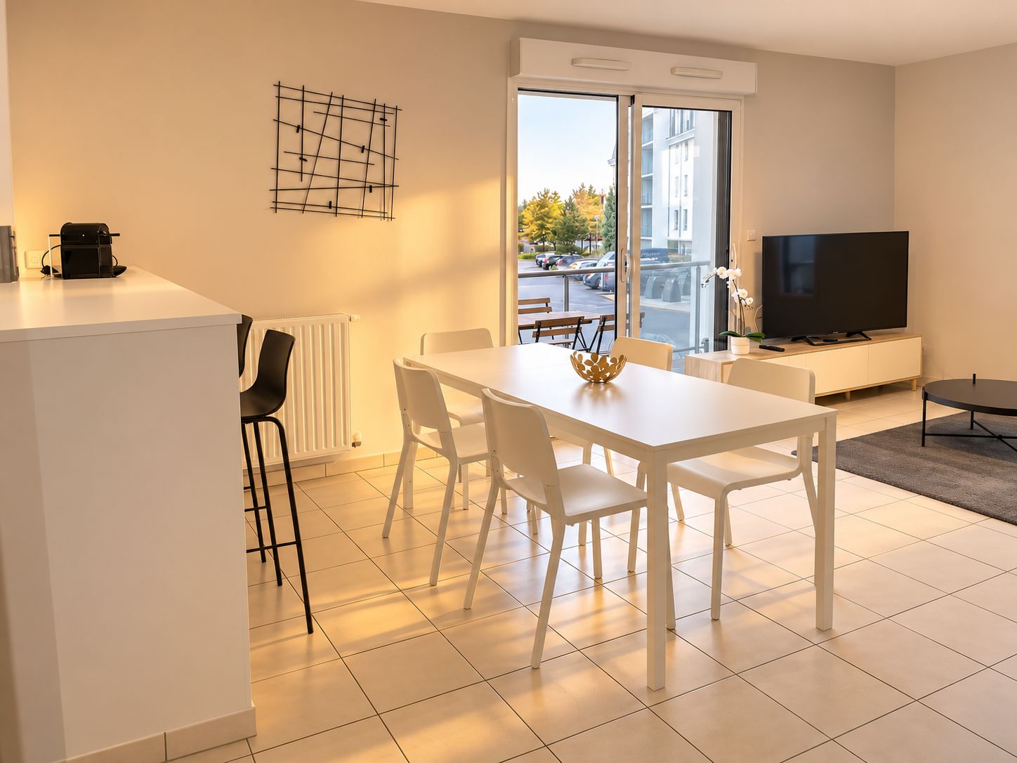 Ein modernes Wohnzimmer mit Essbereich, einem Flachbildfernseher und Blick ins Freie.