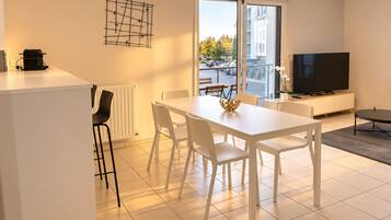 Ein modernes Wohnzimmer mit Essbereich, einem Flachbildfernseher und Blick ins Freie.
