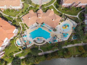An aerial view of a hotel with a central swimming pool, multiple lounge areas, and a landscaped courtyard. - Designer Luxury 3br, Stunning Lake View, Vista Cay (Orlando)