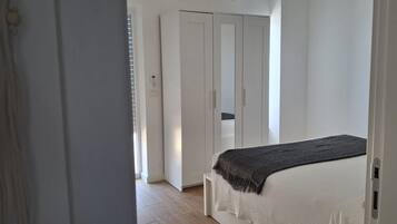 A bedroom with a bed, a wardrobe, and a door leading to another room.