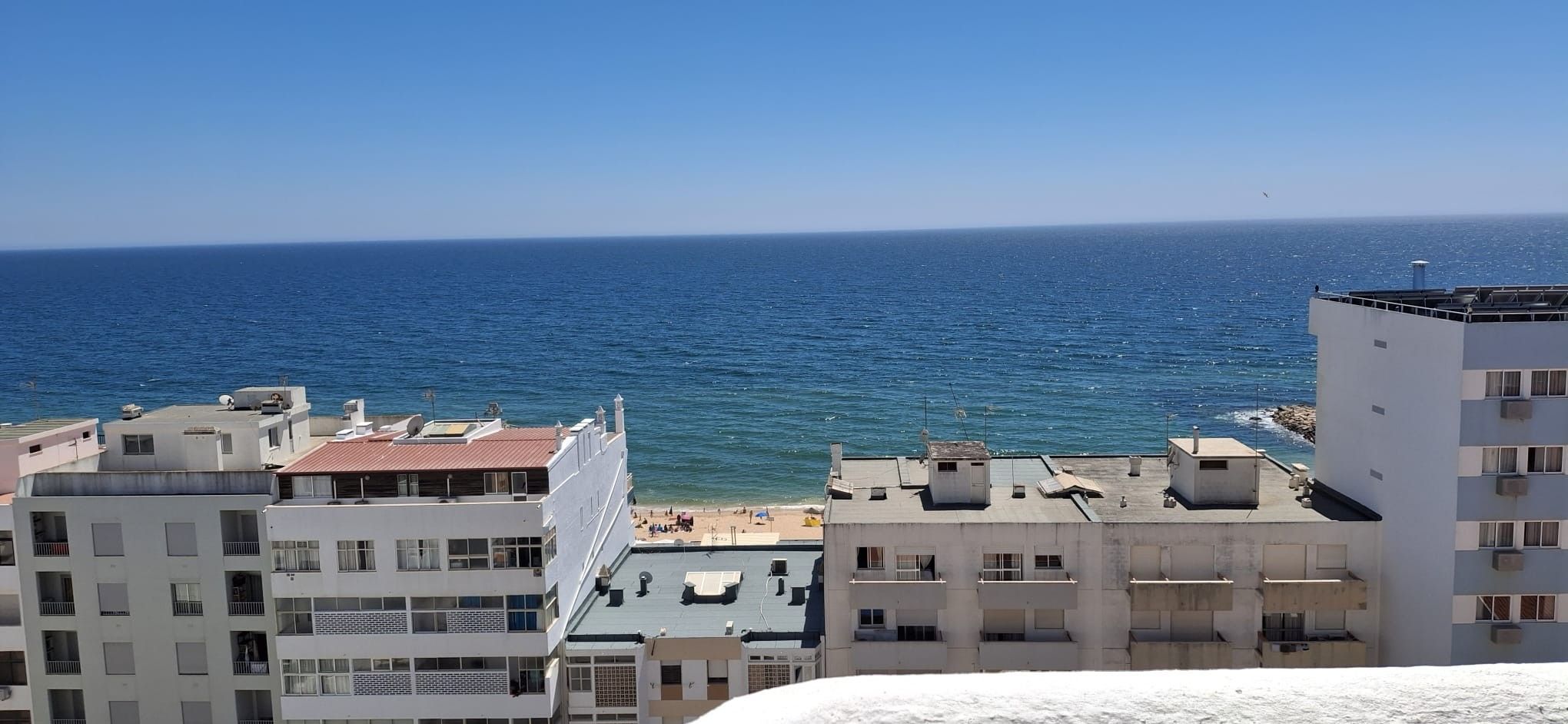 Un paysage urbain côtier avec des bâtiments donnant sur la mer, dotés de balcons et offrant une vue dégagée sur l’océan.