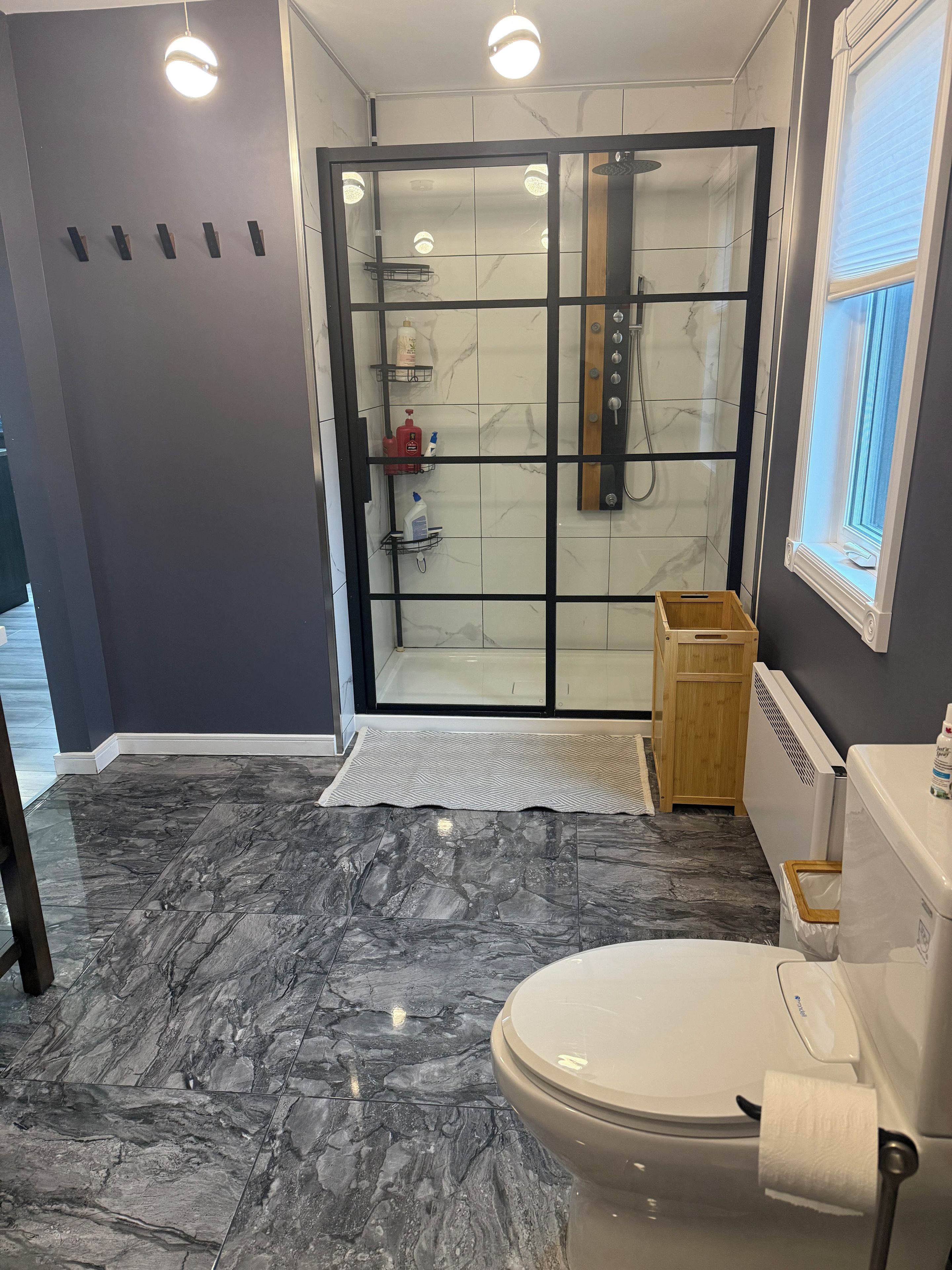 A bathroom with a toilet, a shower with a glass door, and a wooden cabinet.