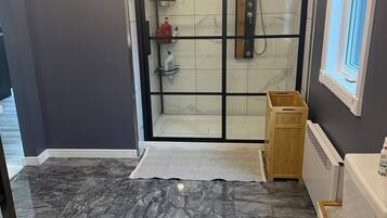 A bathroom with a toilet, a shower with a glass door, and a wooden cabinet.