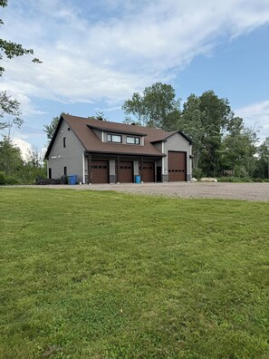 Ein zweistöckiges Haus mit Garage, überdachter Veranda und großem Rasen.