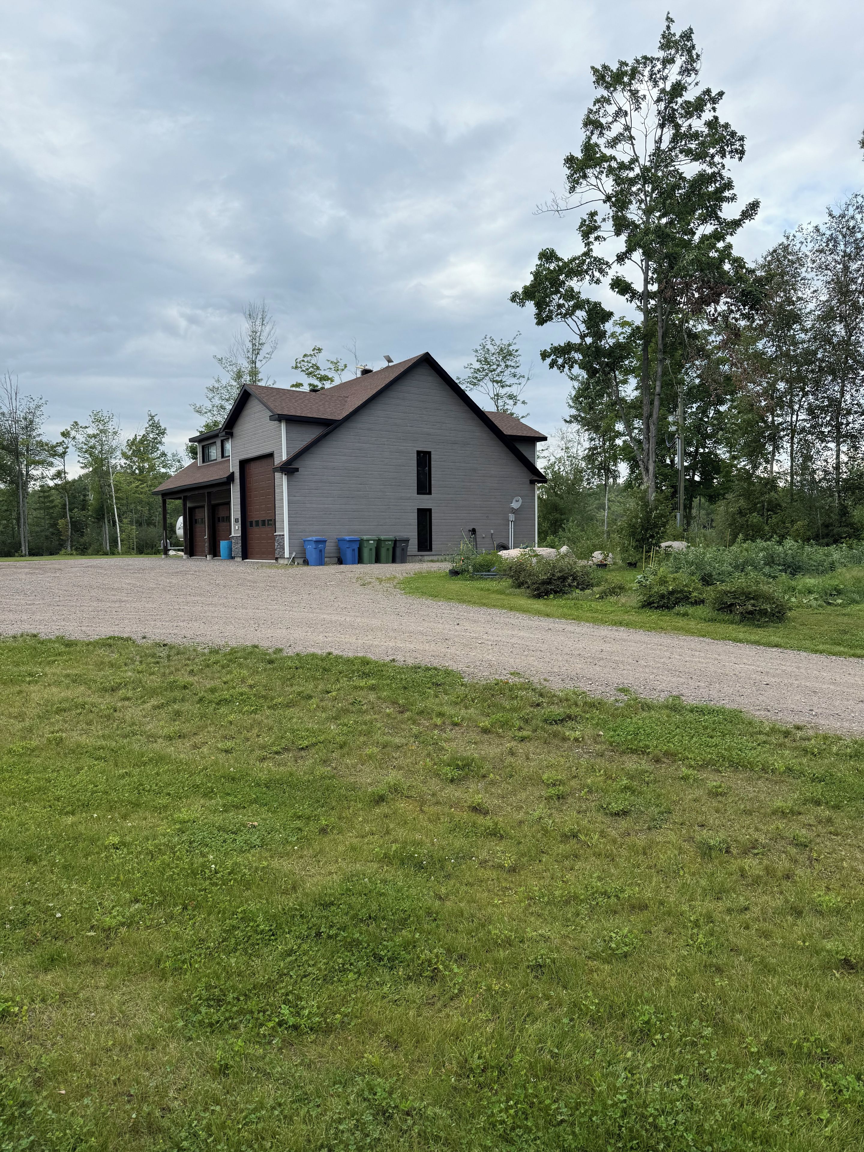 A two-story building with a garage, a covered porch, and a gravel driveway.