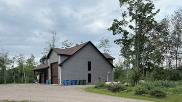 A two-story building with a garage, a covered porch, and a gravel driveway.