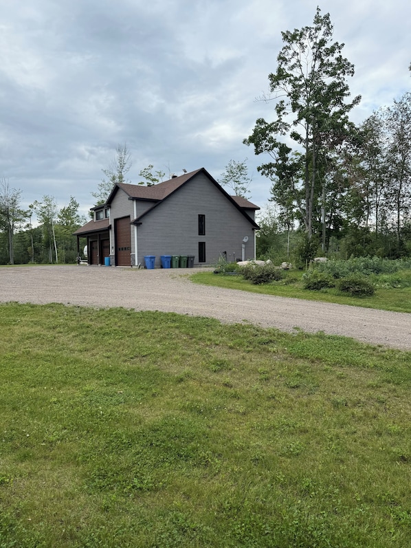 A two-story building with a garage, a covered porch, and a gravel driveway.