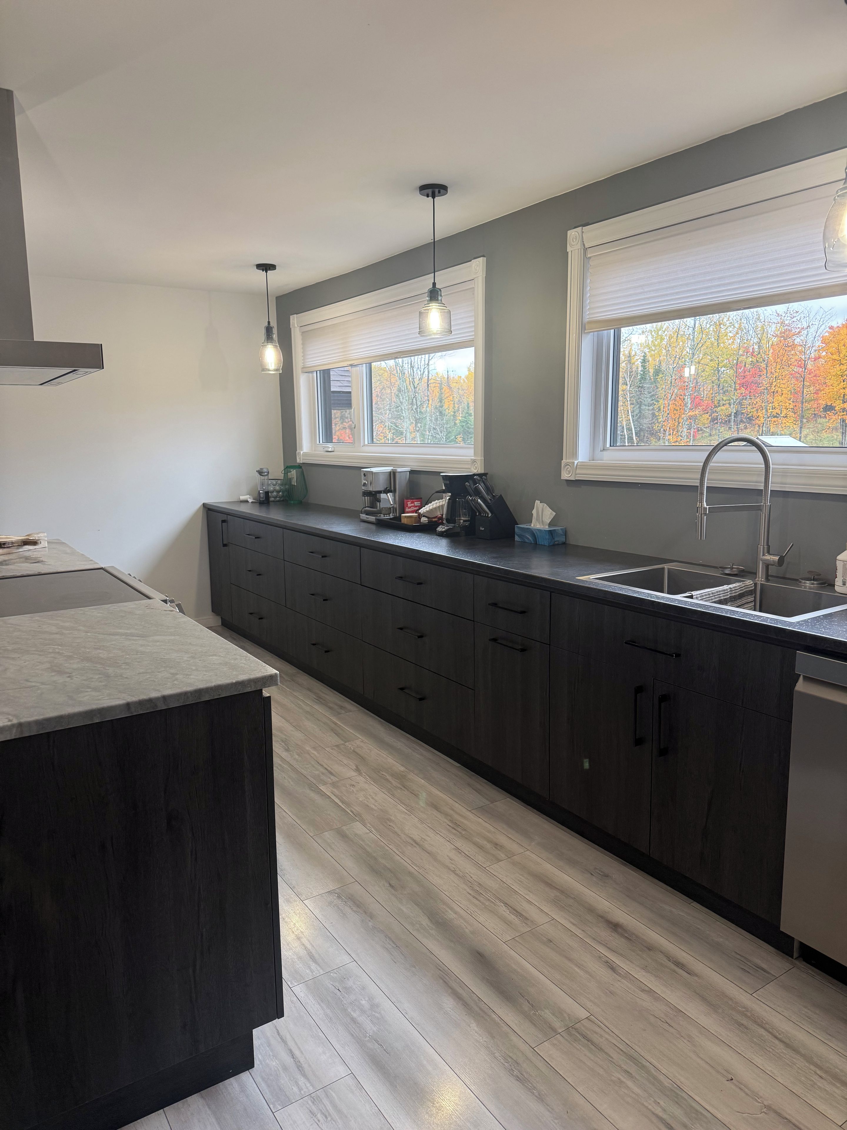 A modern kitchen with dark cabinetry, a central island, a built-in sink, and pendant lighting.