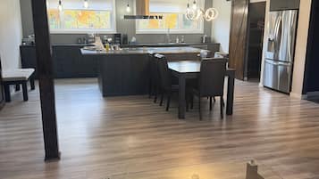 A modern kitchen with a central island, dining area, and a glass-top coffee table.