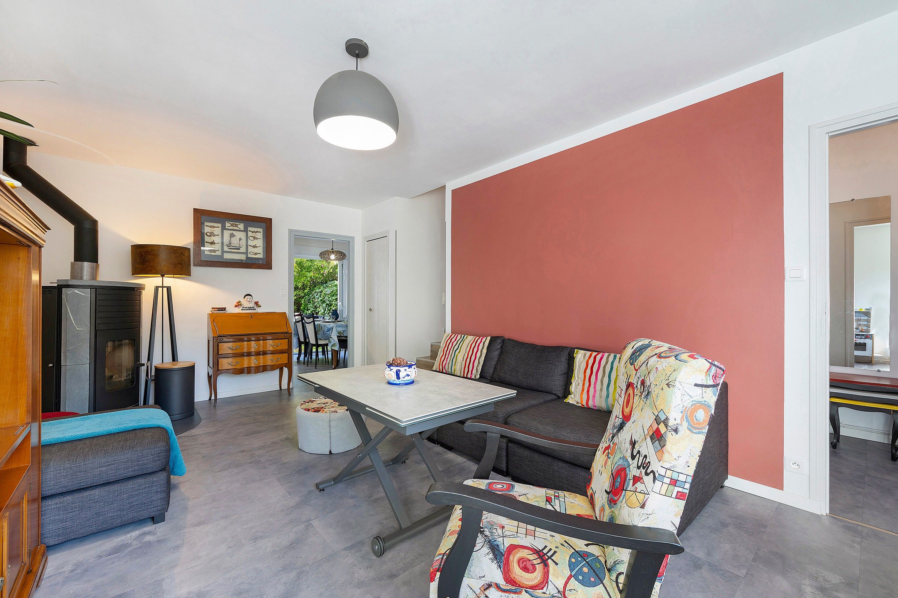 Een kamer met een bank, een tafel, een lamp, een open haard en een deur naar een andere kamer.