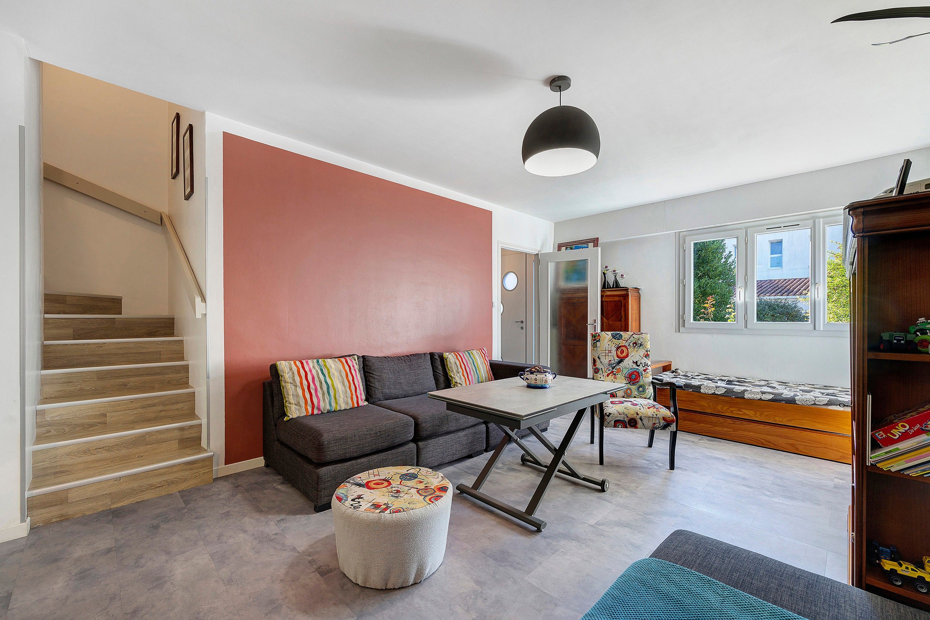 Un salon moderne avec un canapé, un pouf et une table à manger.