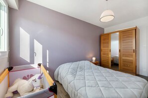 Ein Schlafzimmer mit einem Bett, einem Holzschrank, einem Nachttisch und einer Deckenleuchte.