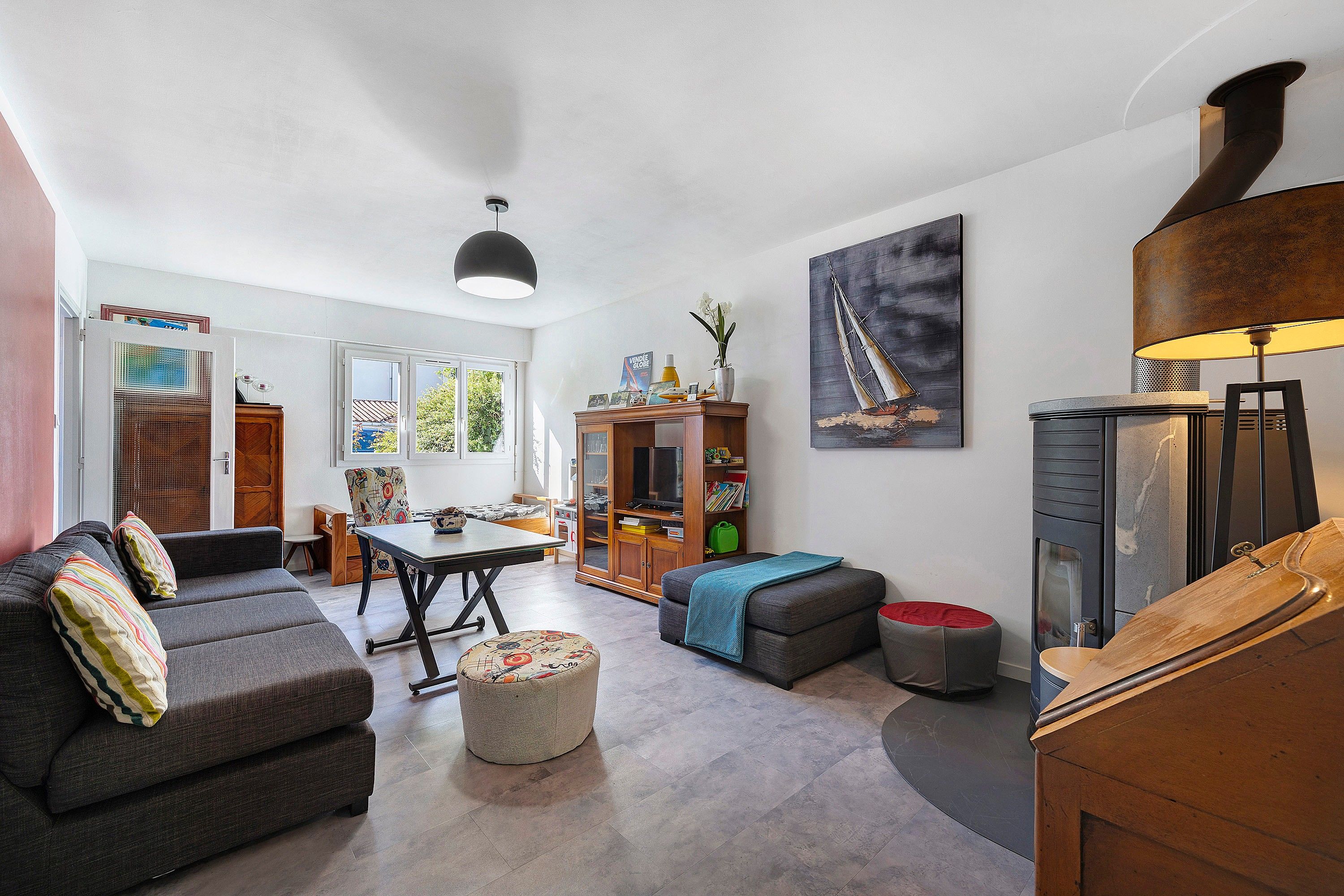 A modern living room with a sofa, ottoman, and a dining table.