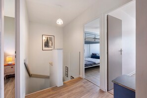 Ein Flur mit einer Treppe, einem Bett mit Etagenhohe Bett, einem Nachttisch mit Lampe und einem gerahmten Bild an der Wand.